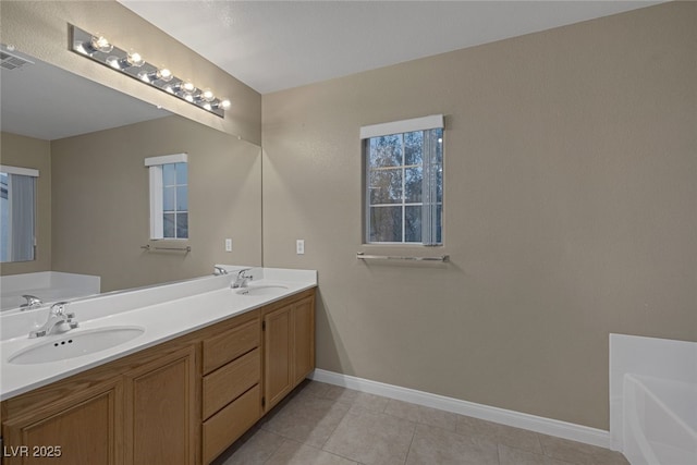 full bathroom featuring a garden tub, a sink, tile patterned flooring, double vanity, and baseboards