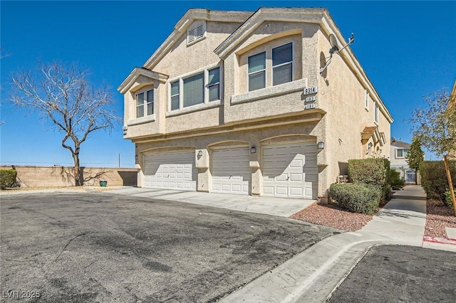 view of front facade with a garage, concrete driveway, and stucco siding