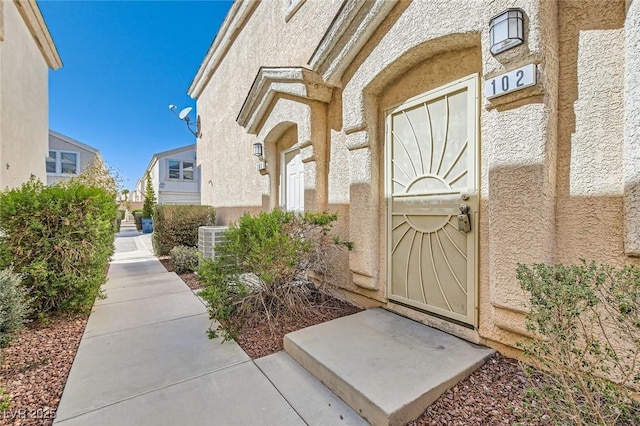 view of exterior entry featuring cooling unit and stucco siding