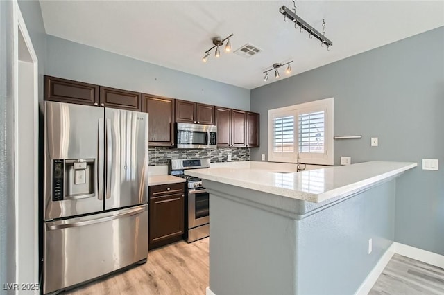 kitchen with visible vents, dark brown cabinets, light countertops, light wood-type flooring, and stainless steel appliances