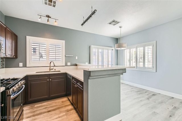 kitchen with a peninsula, stainless steel range with gas stovetop, visible vents, and a sink