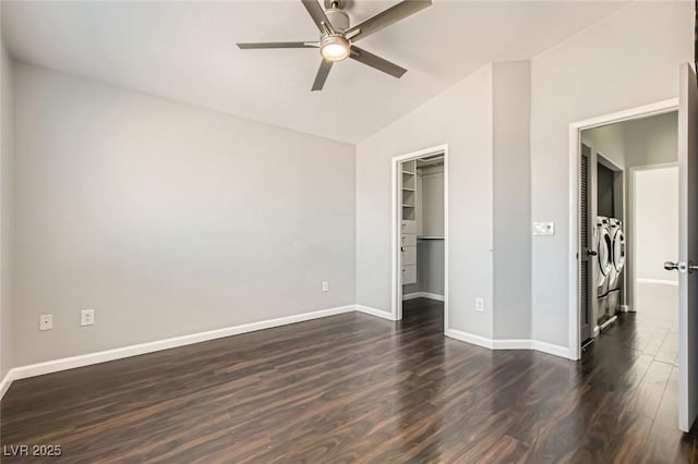 unfurnished bedroom featuring a walk in closet, dark wood-type flooring, a ceiling fan, baseboards, and lofted ceiling