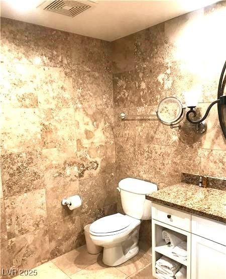 bathroom with toilet, tile patterned flooring, visible vents, and vanity