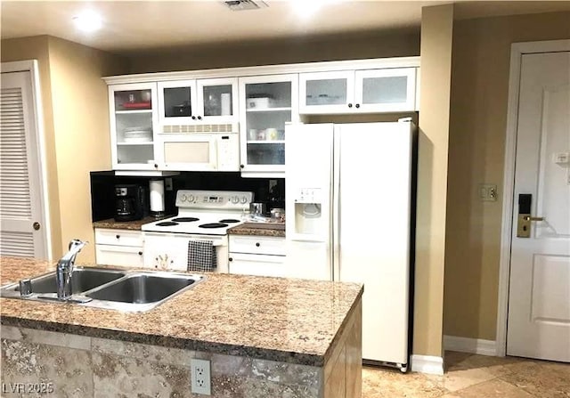 kitchen with glass insert cabinets, white cabinetry, a sink, white appliances, and baseboards