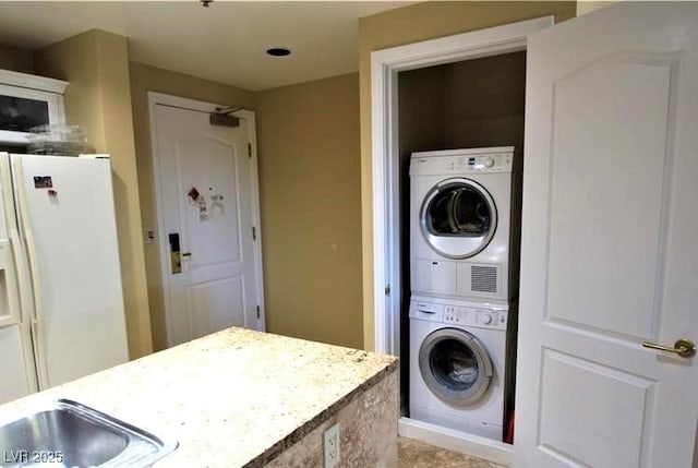 laundry room with stacked washing maching and dryer, laundry area, and a sink