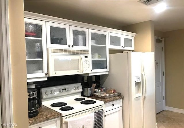 kitchen featuring white appliances, glass insert cabinets, visible vents, and white cabinets