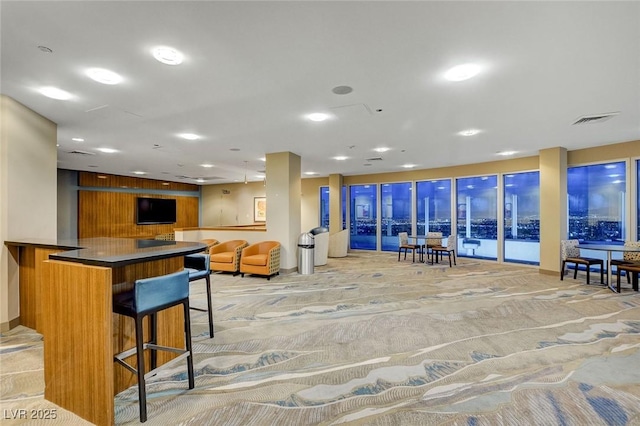 kitchen featuring dark countertops, visible vents, open floor plan, a breakfast bar area, and recessed lighting