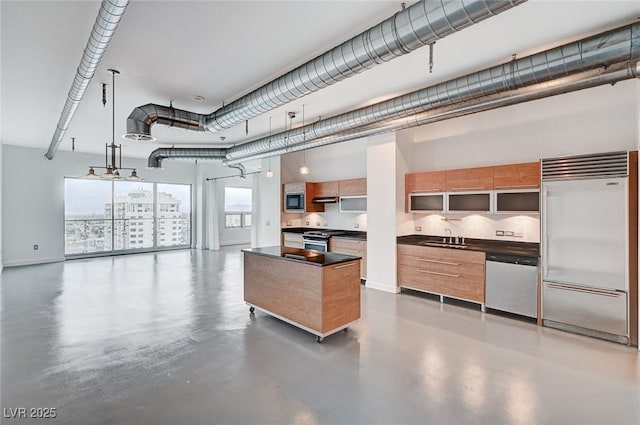 kitchen featuring a sink, dark countertops, open floor plan, finished concrete flooring, and stainless steel appliances