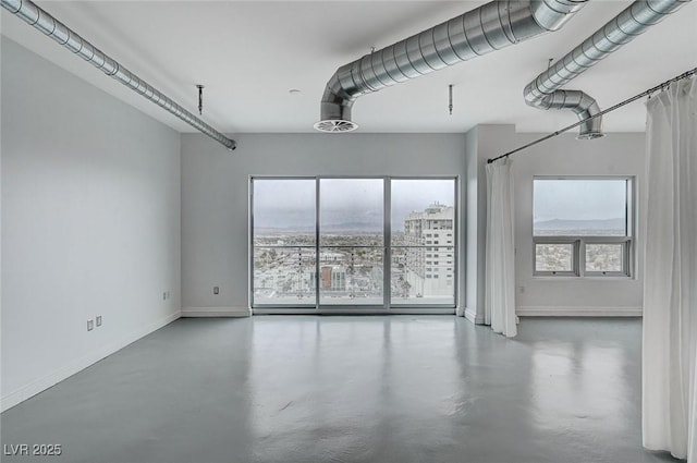 empty room with baseboards, plenty of natural light, and concrete flooring