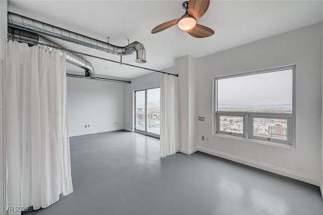 unfurnished room with baseboards, finished concrete floors, and a ceiling fan