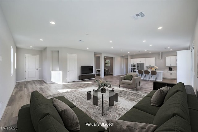 living area with baseboards, recessed lighting, visible vents, and light wood-style floors