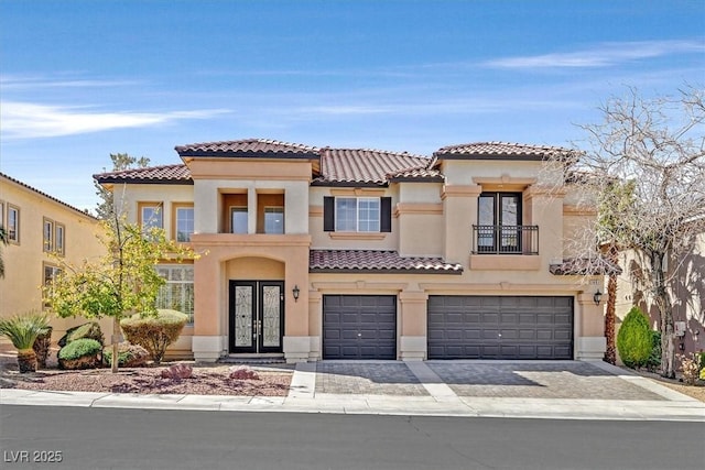 mediterranean / spanish house with french doors, a garage, stucco siding, and a tile roof