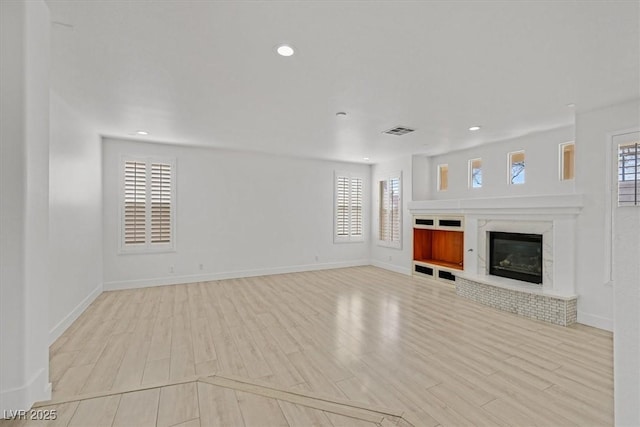 unfurnished living room with recessed lighting, wood finished floors, visible vents, and a wealth of natural light