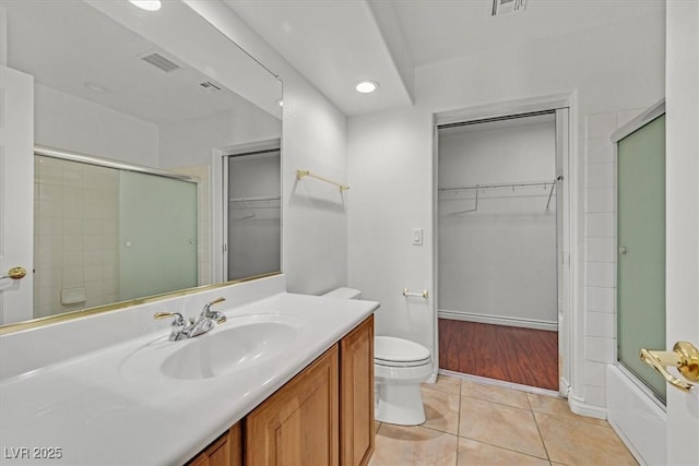 full bath featuring tile patterned flooring, visible vents, a walk in closet, toilet, and vanity