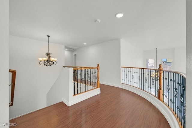 hallway featuring an upstairs landing, wood finished floors, a chandelier, and recessed lighting