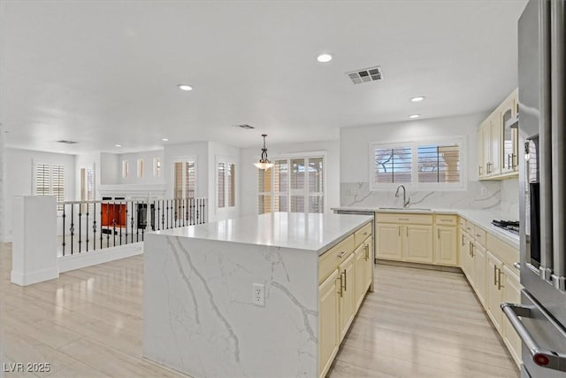 kitchen featuring visible vents, decorative backsplash, appliances with stainless steel finishes, cream cabinets, and a sink