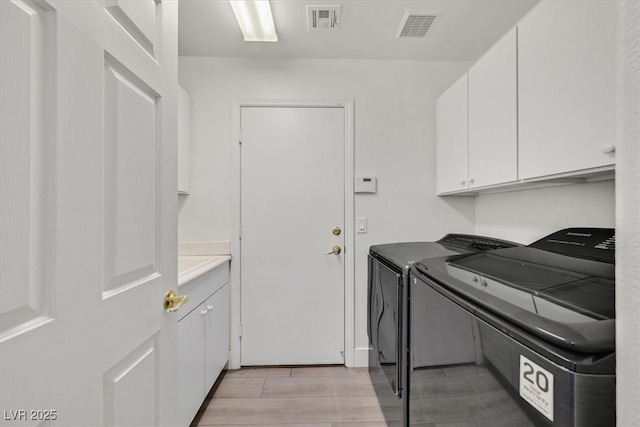 laundry area with visible vents, cabinet space, and separate washer and dryer