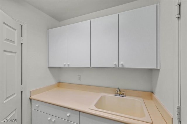 kitchen featuring white cabinets, light countertops, and a sink