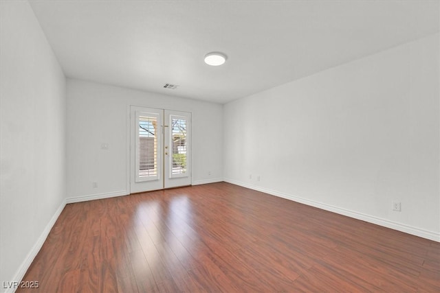 unfurnished room with visible vents, baseboards, and dark wood-style floors