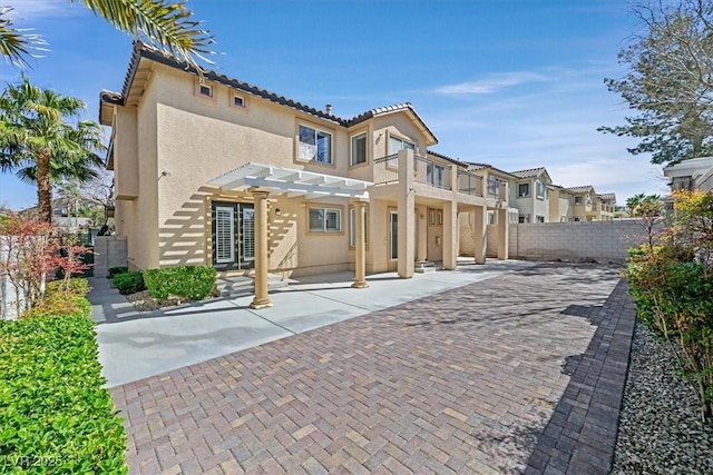 exterior space with fence, a tile roof, stucco siding, french doors, and a pergola