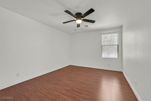 unfurnished room featuring baseboards, dark wood-style floors, visible vents, and ceiling fan