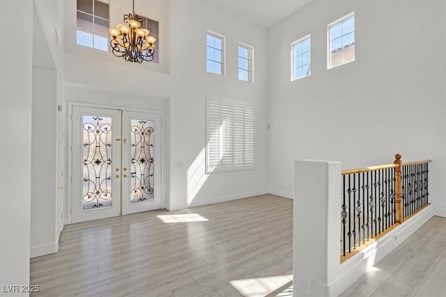 entrance foyer featuring a high ceiling, a notable chandelier, wood finished floors, and baseboards