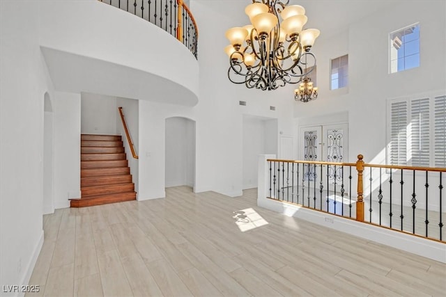 interior space with a high ceiling, a notable chandelier, wood finished floors, and arched walkways
