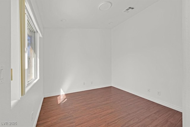 empty room featuring visible vents, baseboards, and wood finished floors