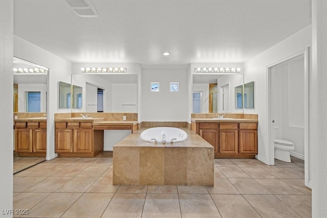 bathroom with tile patterned flooring, two vanities, a bath, and a sink