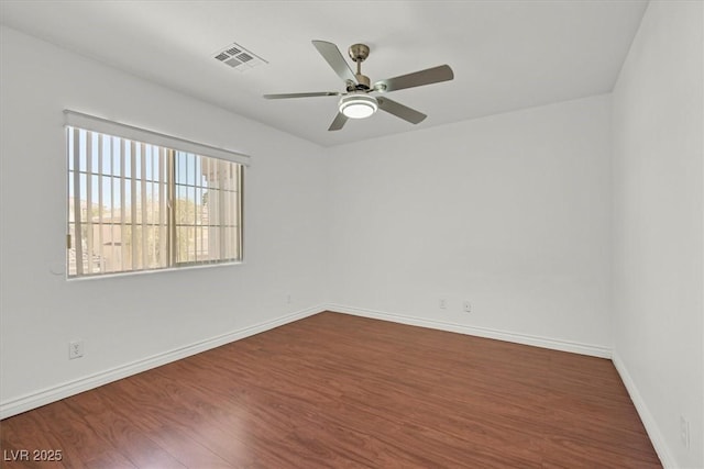 spare room with visible vents, baseboards, dark wood-type flooring, and ceiling fan