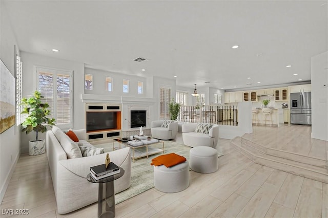 living area featuring light wood-style flooring, recessed lighting, visible vents, and a wealth of natural light