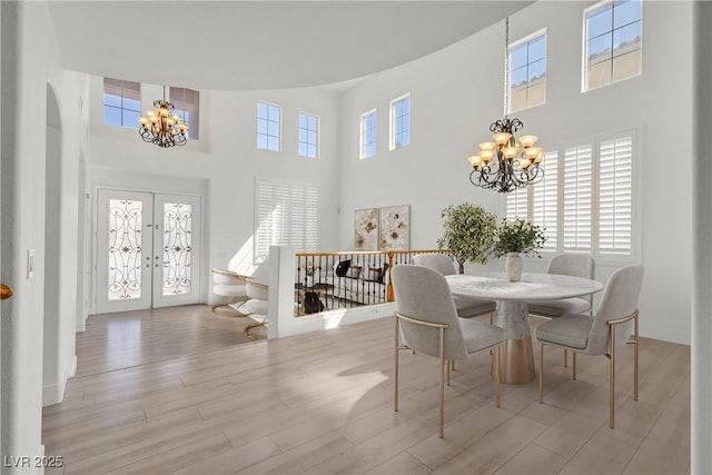 dining space with french doors, plenty of natural light, an inviting chandelier, and wood finished floors