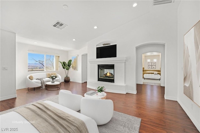 living room featuring a multi sided fireplace, visible vents, recessed lighting, and wood finished floors