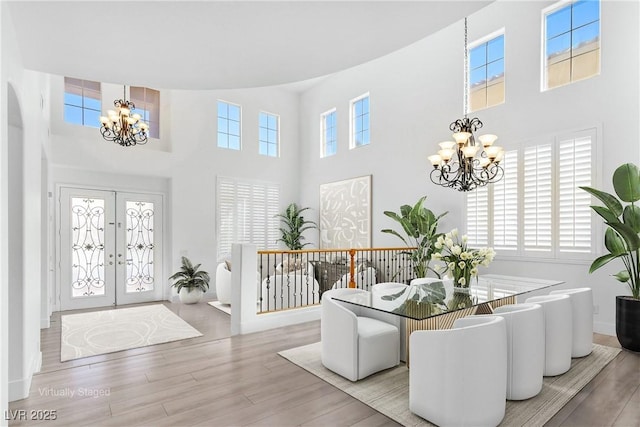 foyer entrance with french doors, plenty of natural light, a notable chandelier, and wood finished floors