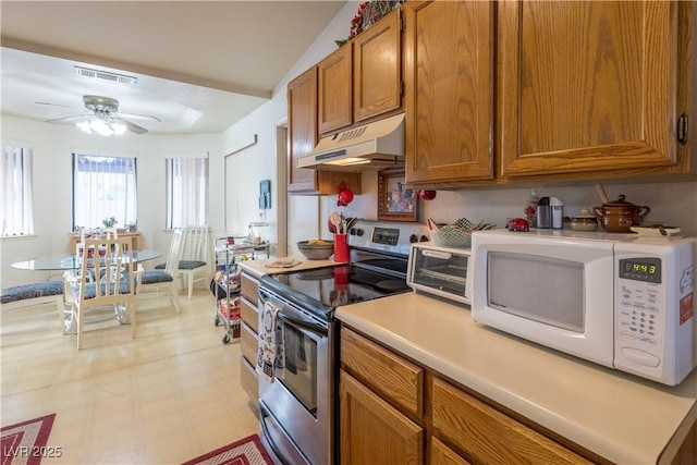 1892 Maricopa Dr, Laughlin, NV 89029 - kitchen with visible vents, white microwave, stainless steel electric range oven, brown cabinets, and under cabinet range hood