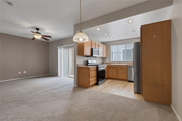 kitchen with light colored carpet, stainless steel appliances, a sink, open floor plan, and light countertops