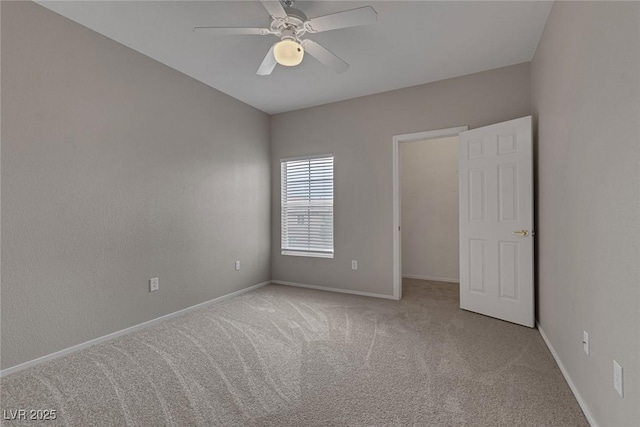 carpeted empty room with a ceiling fan and baseboards