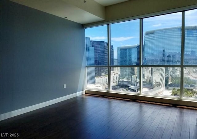 spare room featuring dark wood-style floors, baseboards, and a city view