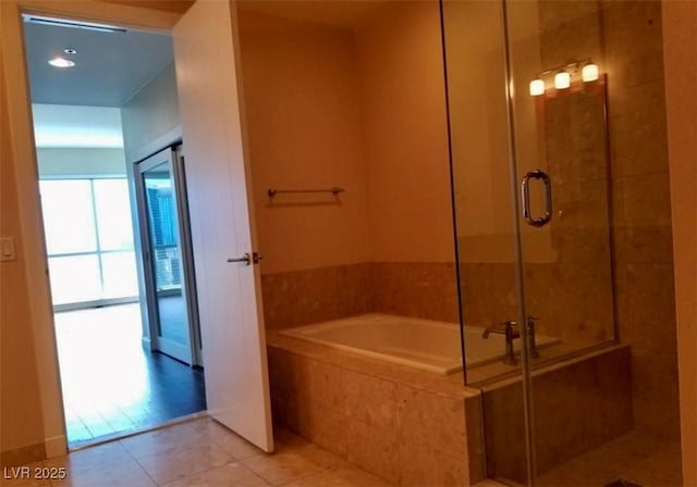 bathroom with a stall shower, a bath, and tile patterned floors