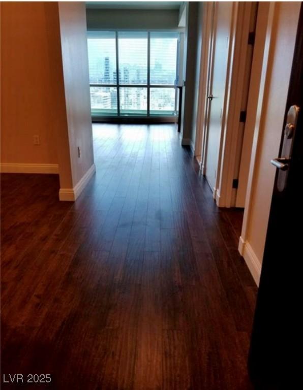 hallway featuring dark wood-style flooring and baseboards