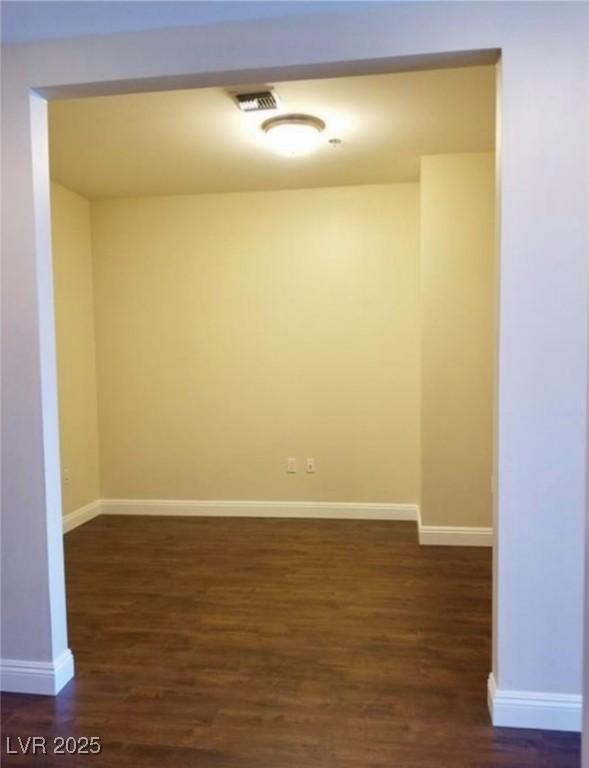 spare room featuring dark wood-style floors, visible vents, and baseboards