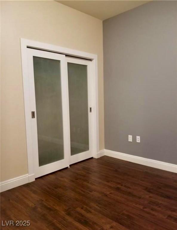 spare room with dark wood-type flooring and baseboards