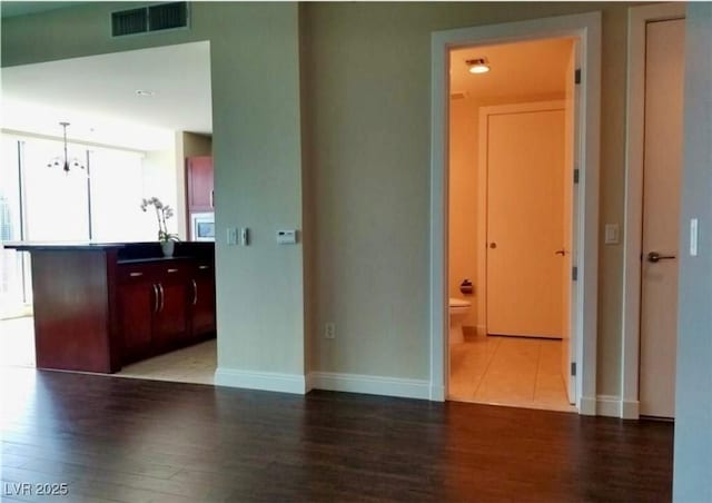 interior space with wood finished floors, visible vents, and baseboards