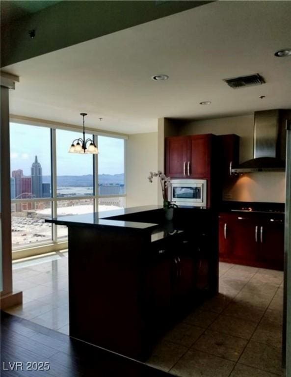 kitchen with reddish brown cabinets, dark countertops, stainless steel microwave, wall chimney range hood, and floor to ceiling windows