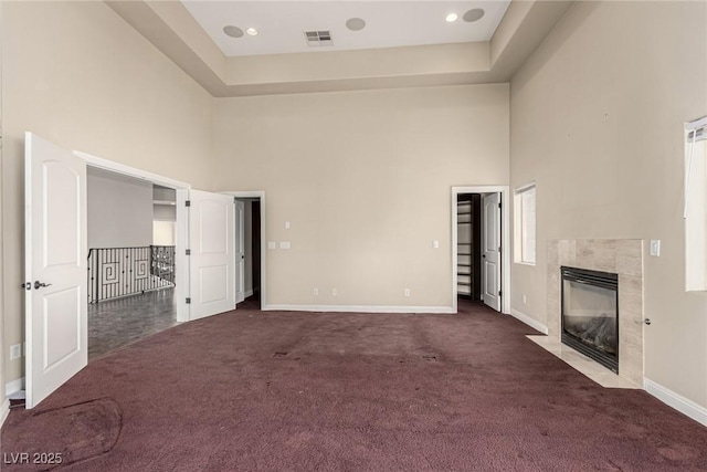 unfurnished bedroom with baseboards, a high ceiling, dark carpet, and a fireplace