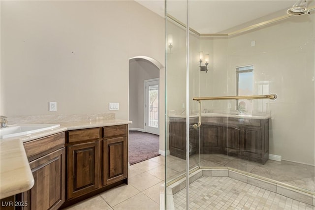 bathroom with a shower with door, vanity, a towering ceiling, and tile patterned floors