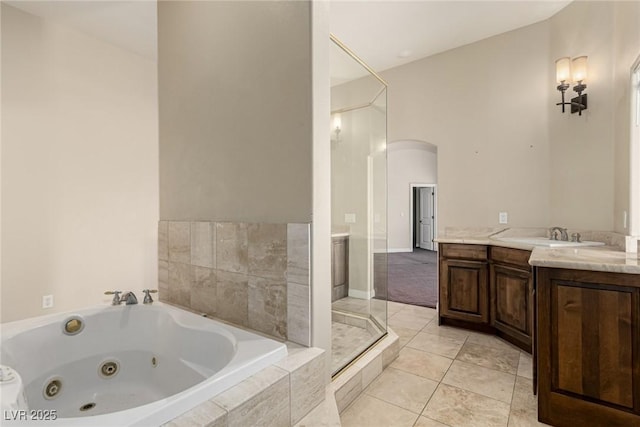 bathroom featuring walk in shower, vanity, a tub with jets, and tile patterned floors