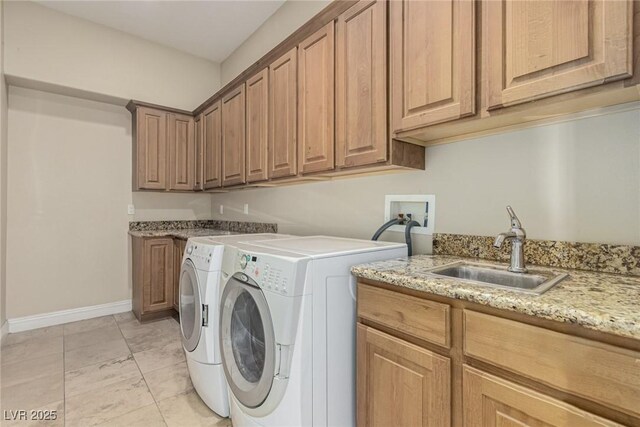 clothes washing area with cabinet space, a sink, baseboards, and separate washer and dryer