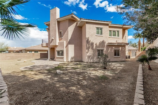 back of property with a chimney, stucco siding, a patio area, fence, and a tiled roof