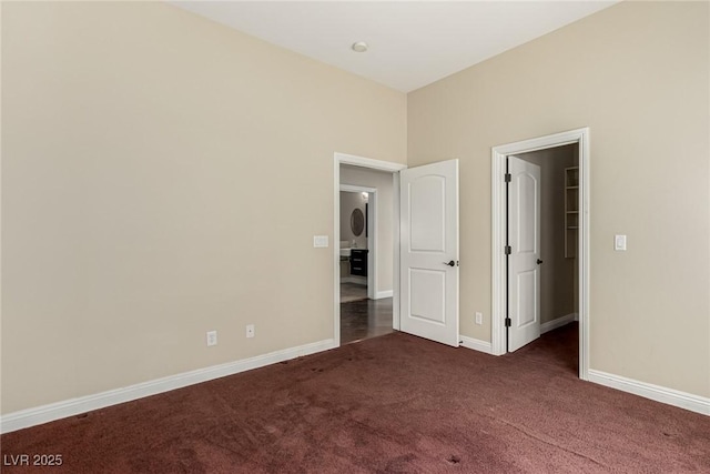 unfurnished bedroom with a spacious closet, baseboards, and carpet flooring